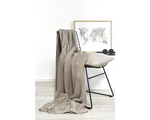 Beige Strickdecke über einem Stuhl mit Weltkarte im Hintergrund