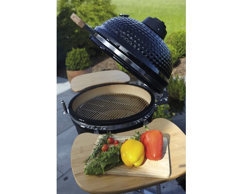 Keramikgrill mit Grillrost und Gemüse auf einem Schneidebrett