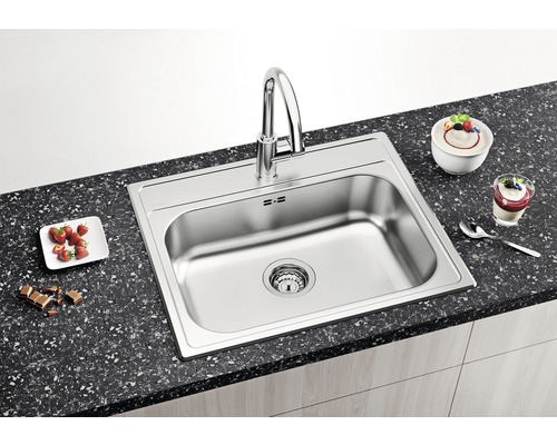 Évier en acier inoxydable avec robinetterie sur un comptoir de cuisine avec des aliments.