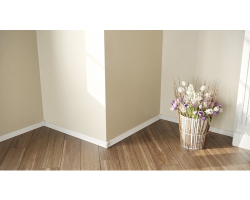 Coin de pièce avec parquet, plinthes blanches et arrangement floral dans un panier