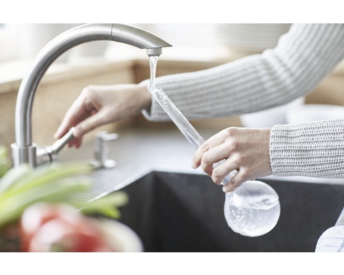 Eine Person füllt einen Eisballbereiter unter einem Wasserhahn.