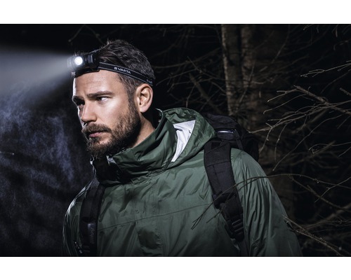 Homme avec lampe frontale Varta et sac à dos à l''extérieur