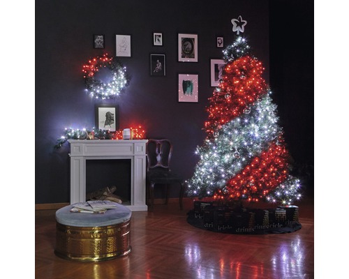 Salon décoré pour Noël avec sapin, guirlandes lumineuses, cheminée et tableaux au mur.