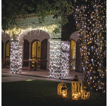 Bâtiments décorés et arbre avec guirlandes lumineuses et lanternes dans le jardin pour une ambiance chaleureuse.