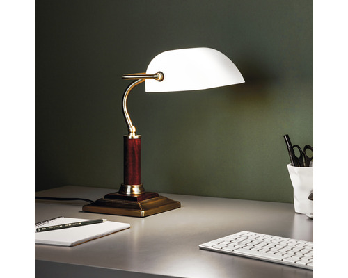 Lampe de table avec abat-jour en verre sur un bureau avec bloc-notes et clavier.