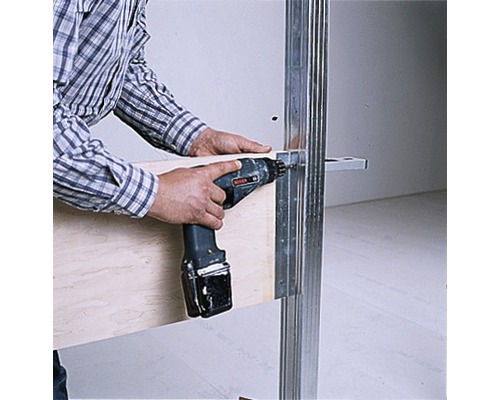 Une personne fixe une planche de bois sur un montant métallique à l''aide d''une visseuse sans fil.