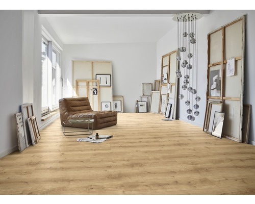 Heller Raum mit Laminatboden, Sessel und Kunstwerken.