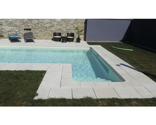 Piscine avec bordure en pierre et mobilier de jardin