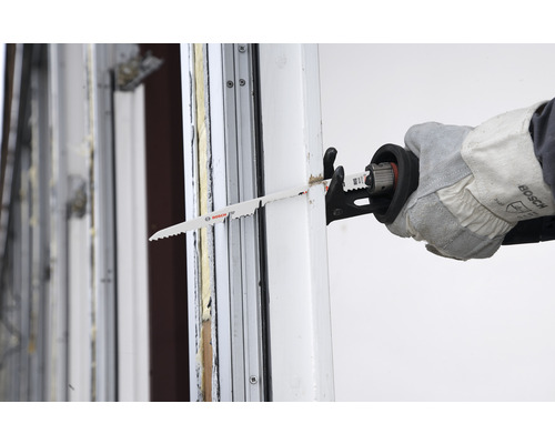 Eine Stichsäge schneidet durch einen Fensterrahmen