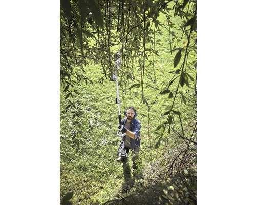 Un homme utilise un ébrancheur dans le jardin.