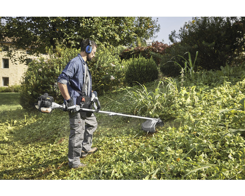 Un homme travaille avec un coupe-bordure dans le jardin