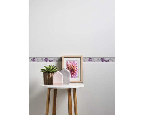 Scène avec bordure, cadre photo, plante et décoration sur une table.