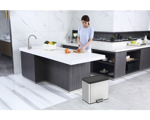 Cuisine claire avec îlot de cuisine, évier, poubelle et femme cuisinant