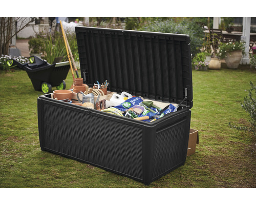 Coffre de jardin noir ouvert rempli d''outils de jardinage dans le jardin