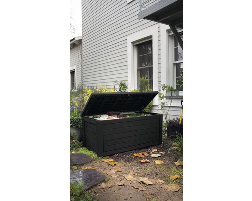 Geöffnete, schwarze Gartenbox auf einer Rasenfläche vor einem Haus