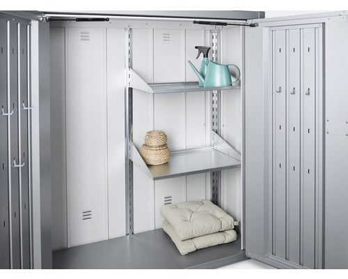 Innenraum eines Metall Gerätehauses mit Regalen, Kissen und einer Gießkanne