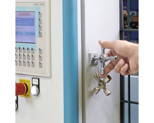 Un homme actionne une armoire électrique avec une clé universelle.