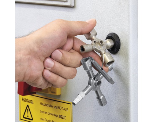 Main actionnant une clé multifonction sur une armoire électrique