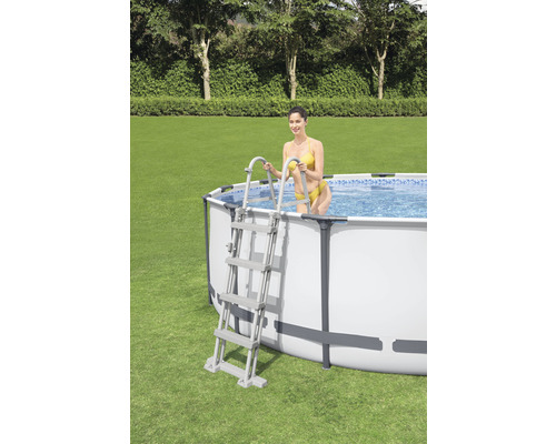 Aufstellpool mit Leiter und Frau im Garten.