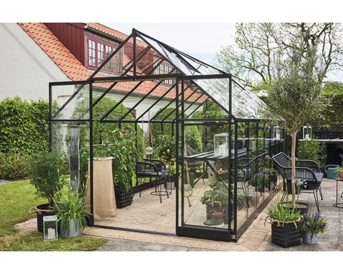 Gewächshaus mit Pflanzen und Gartenmöbeln im Außenbereich.