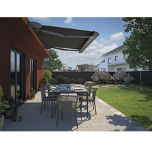 Terrasse avec store, table de jardin et chaises devant une maison