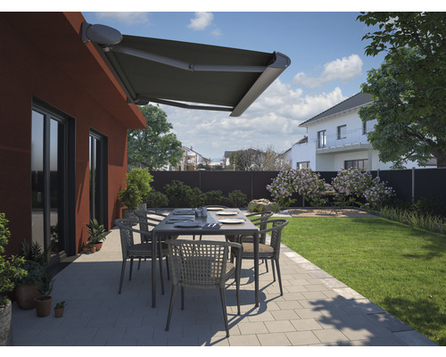 Terrasse avec store, table de jardin et chaises devant une maison