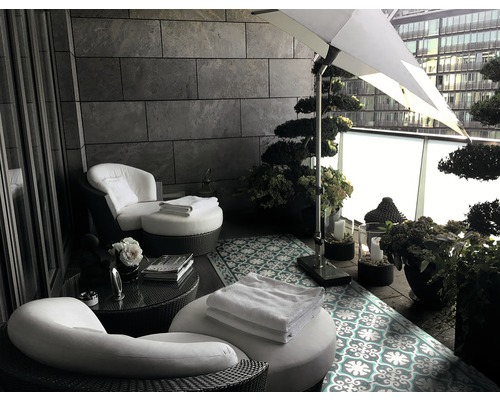 Einrichtung eines Balkons mit Lounge-Sesseln, Beistelltisch, Sonnenschirm und Dekoration