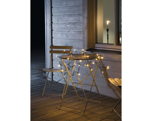 Filet lumineux Konstsmide 96 LED 3 m + alimentation 10 m couleur d'éclairage ambre Scène de jardin avec guirlande lumineuse sur table et chaises sur une terrasse