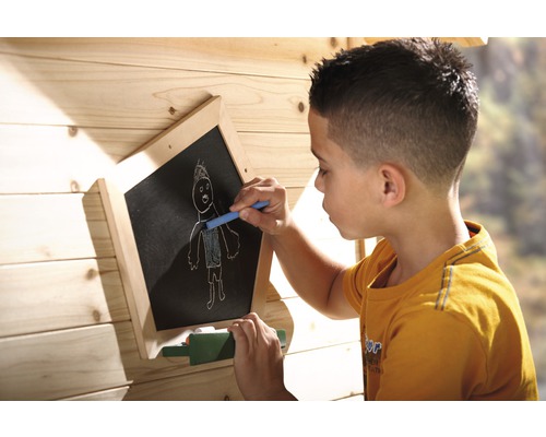 Junge zeichnet mit Kreide auf eine Maltafel im Spielhaus