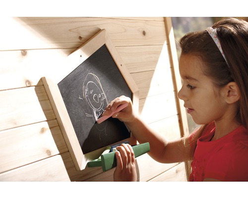 Mädchen zeichnet mit Kreide auf einer Holztafel im Garten