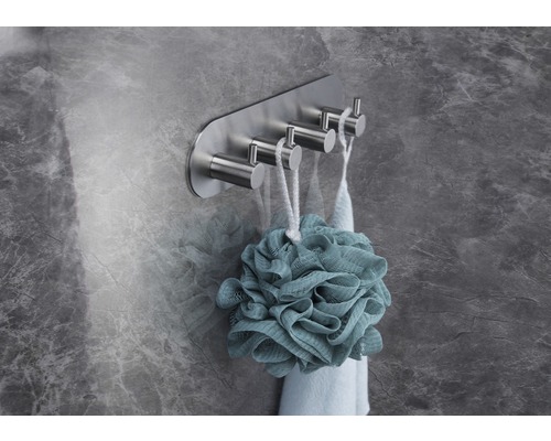 Handtuchhalter mit vier Haken aus Metall an einer Wand mit einem Badeschwamm.