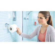 Frau nimmt Toilettenpapier aus einem Toilettenpapierhalter im Badezimmer