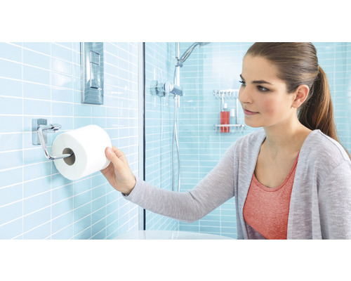 Frau nimmt Toilettenpapier aus einem Toilettenpapierhalter im Badezimmer