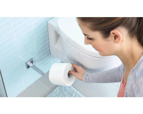 Frau nimmt Toilettenpapier von einem Toilettenpapierspender im Badezimmer