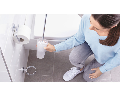Une femme nettoie les toilettes avec une brosse dans la salle de bain.