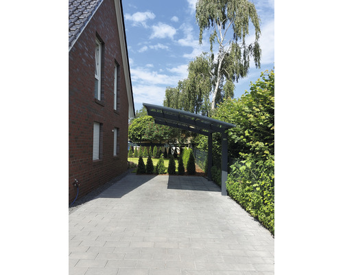 Allée avec pavés et abri de voiture à côté d''une maison en briques