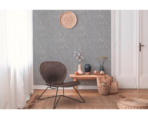 Dekorativer Wohnraum mit Rattansessel, gemusterter Tapete und Holzfußboden