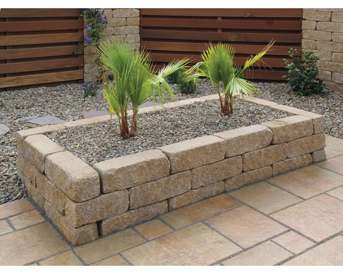Jardinière surélevée en blocs de pierre avec plantes et gravier dans le jardin