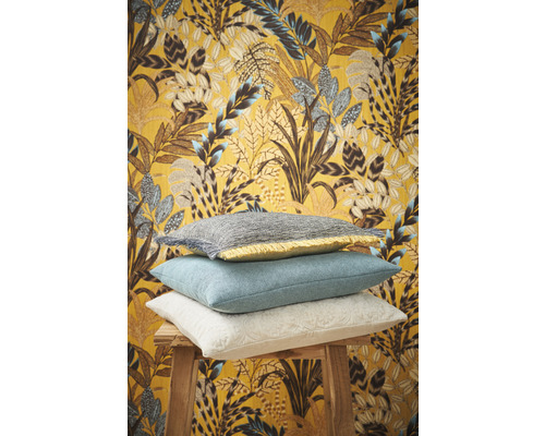 Dekorative Kissen auf einem Hocker vor einer gemusterten Tapete