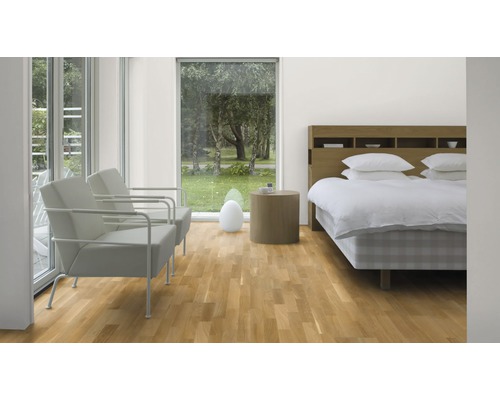 Helles Schlafzimmer mit Parkettboden, Doppelbett, Nachttisch und zwei Sesseln