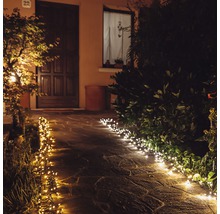 Chemin de jardin illuminé avec des guirlandes lumineuses le soir.