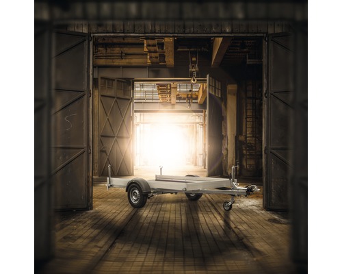Remorque dans un hall industriel avec portes ouvertes.