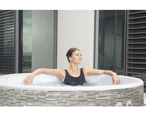 Frau entspannt in einem Outdoor Whirlpool mit Steinverkleidung