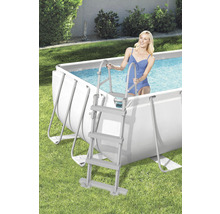 Szene mit einem Stahlrahmenpool und einer Frau, die über eine Poolleiter ins Wasser steigt