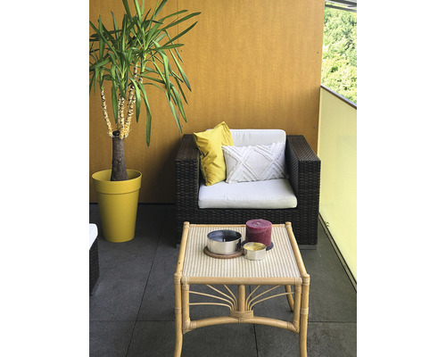 Balkon mit Korbsessel, Tisch, Kissen und Yucca-Palme im Topf