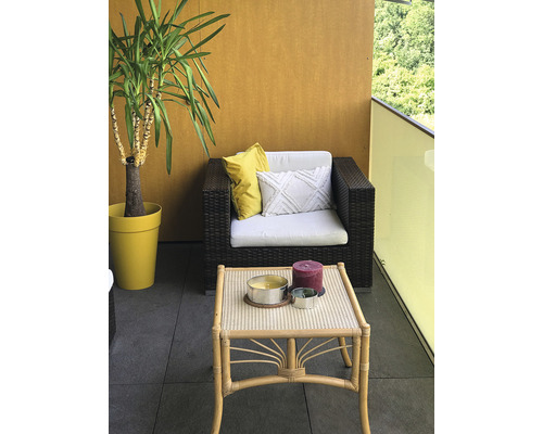 Balkonszene mit Rattansessel, Tisch, Dekoration und Zimmerpflanze im Topf