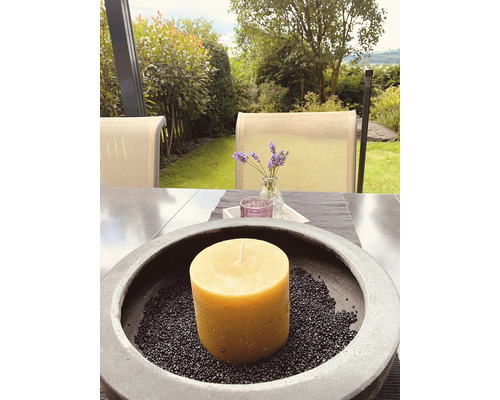 Dekorative Kerze in Schale mit Steinen auf Gartentisch