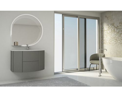 Badezimmer mit Waschtisch, beleuchtetem Spiegel und Badewanne vor einem Fenster