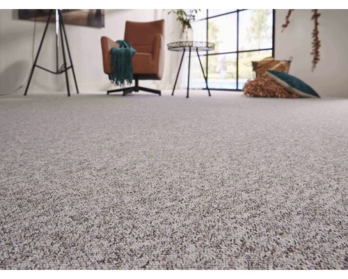 Nahaufnahme eines hellen Teppichs in einem Wohnzimmer mit Sessel, Tisch und Dekoration