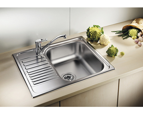 Spüle aus Edelstahl mit Abtropffläche und Armatur auf einer Küchentheke.